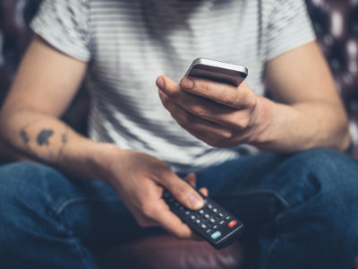 Jeune qui contrôle la télévision avec son téléphone au lieu de la télécommande